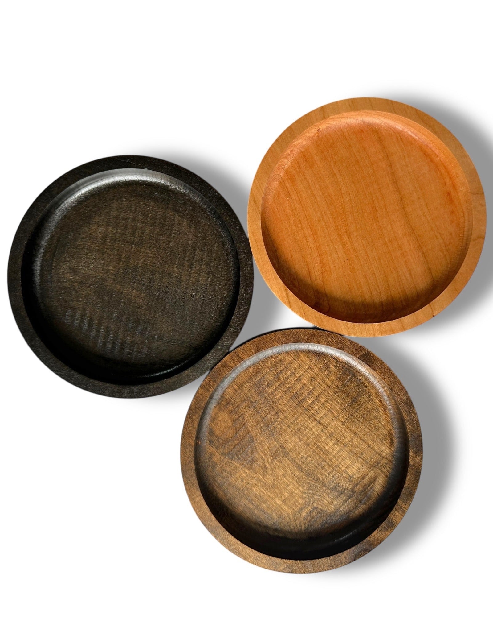 Three round wooden ring dishes arranged in a triangular composition on a white background.