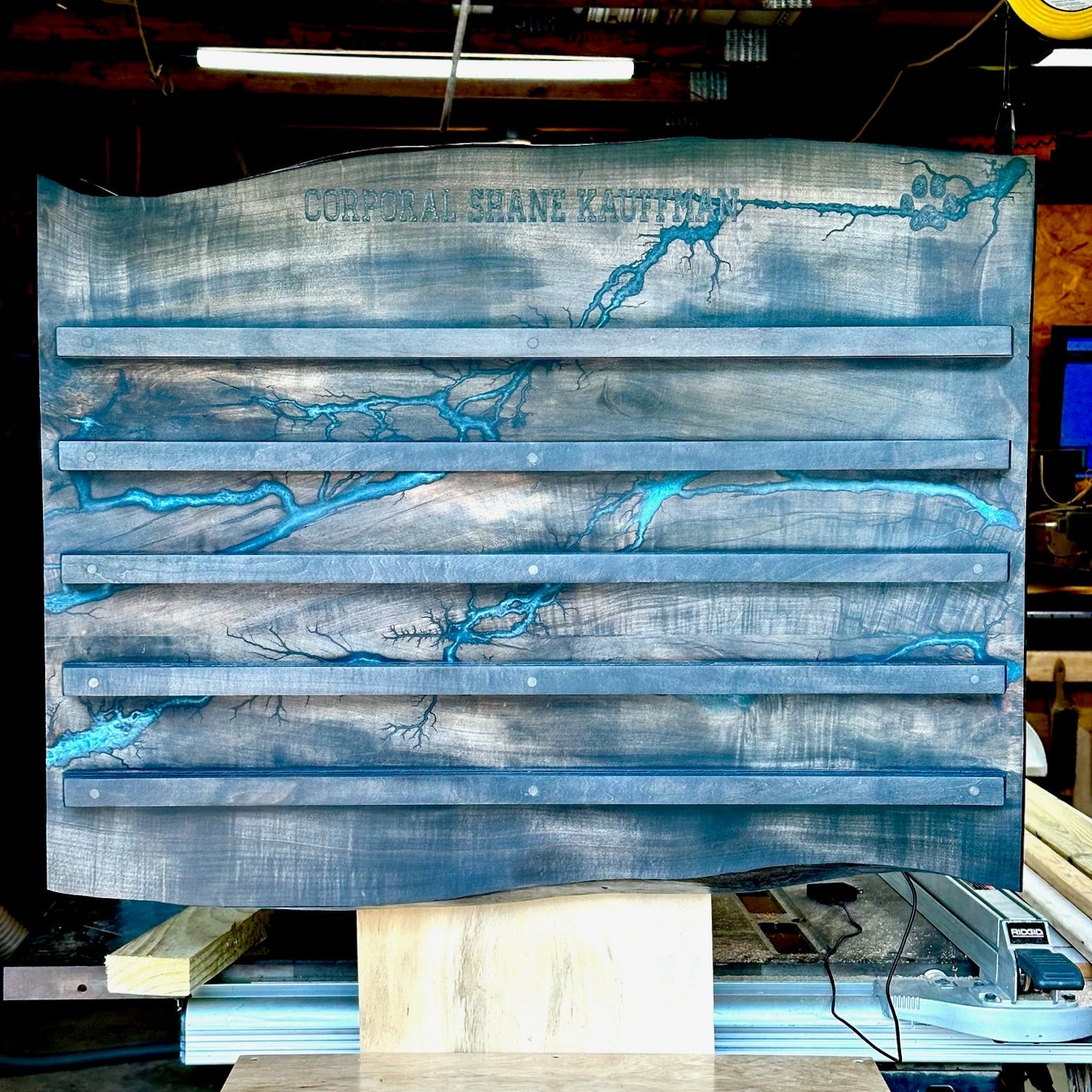 A large decorative wooden wall mounted challenge coin holder featuring a blue and gray distressed wood finish and bright turquoise river-like veining.