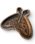 Wooden moth-shaped jewelry dish with engraved designs on a white background