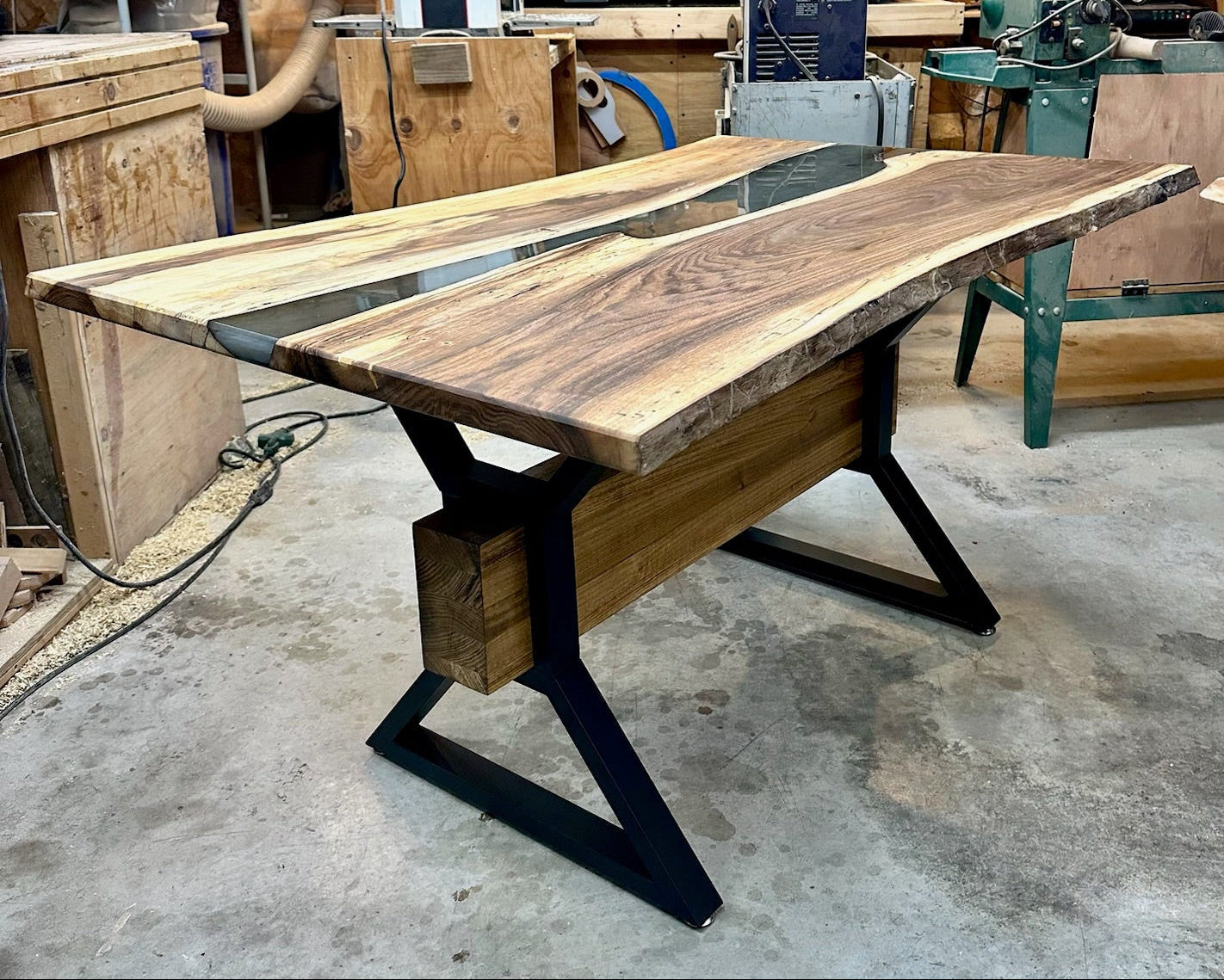 Walnut and green resin table with black metal legs in a wood shop setting