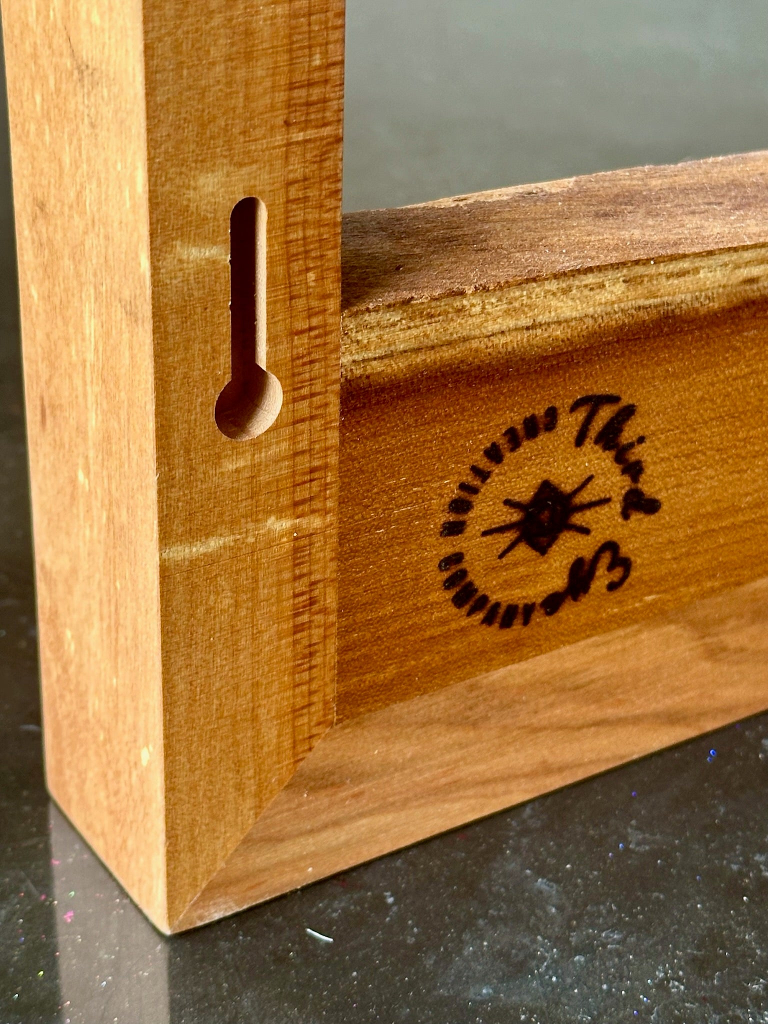 Close-up of a wooden picture frame corner with a keyhole-shaped cutout 