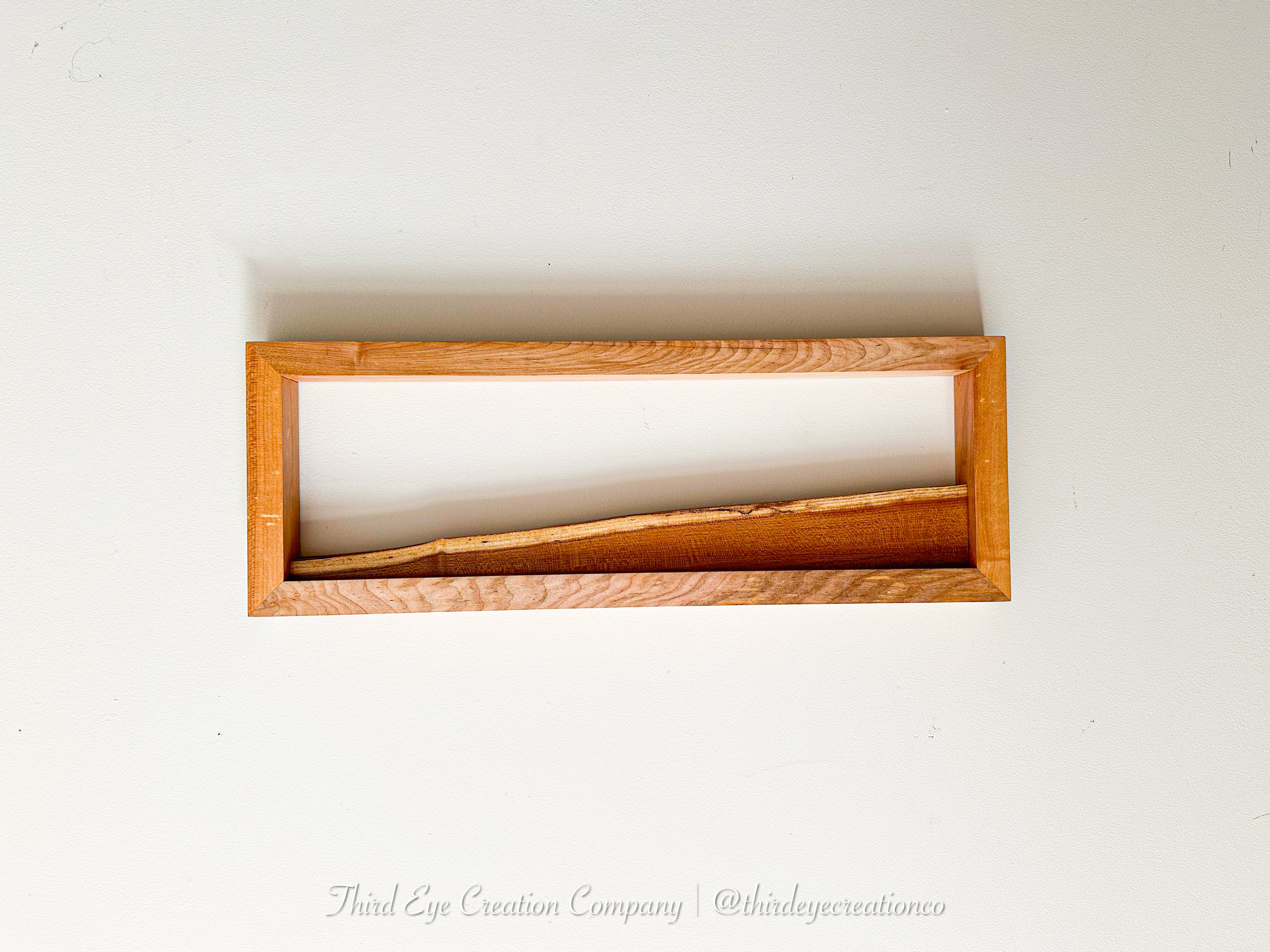 A rectangular wooden frame with a natural live edge, shown empty against a plain white background.