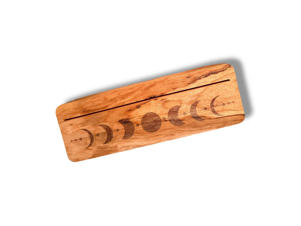 A rectangular wood block featuring an engraved moon phase sequence on the lid with a slit to hold cards