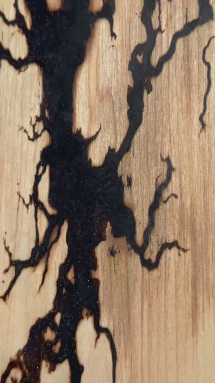 Fractal burned serving board with galaxy black resin inlay shot outside in the trees